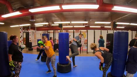 Estudiantes-Adultos-Practicando-Patadas-Inversas-Mientras-Participan-En-Una-Clase-De-Autodefensa-En-La-Escuela-De-Artes-Marciales