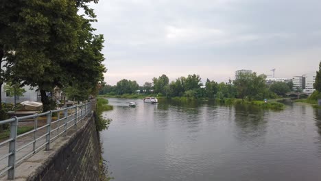 Boats-coming-in-at-Odra-River-in-Wroclaw-city-center,-Pan-shot