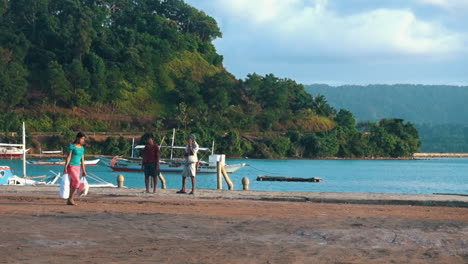 Mujer-Filipina-Caminando-Con-Bolsas-En-El-Puerto-Filipino-Vigilado-Por-Dos-Hombres-En-Un-Día-Soleado