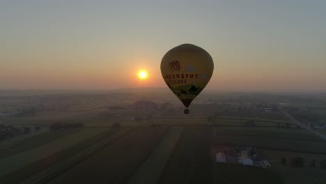 Sunrise-of-a-Hot-Air-Balloon-on-a-Misty-Morning-Over-Amish-Farmlands-as-Seen-by-a-Drone