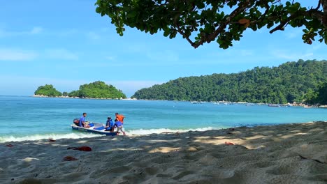 Morgenaufnahme-Einer-Natur-Mit-Einem-Touristen,-Der-Auf-Einem-Kleinen-Boot-Fährt-Und-Das-Meer-Verlässt,-Mit-Bäumen,-Weißem-Sand-Und-Blauem-Himmel-Im-Hintergrund