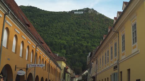 Abwärtsneigung-Von-Den-Bergen-Zur-Marktstraße,-Die-Das-Brasov-Schild-In-Brasov,-Rumänien,-Versteckt