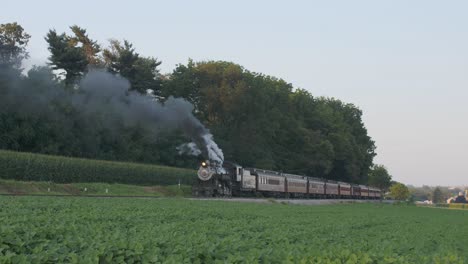 A-1924-Steam-Engine-with-Passenger-Train-Puffing-Smoke-Traveling-Along-the-Amish-Countryside-on-a-Summer-Day