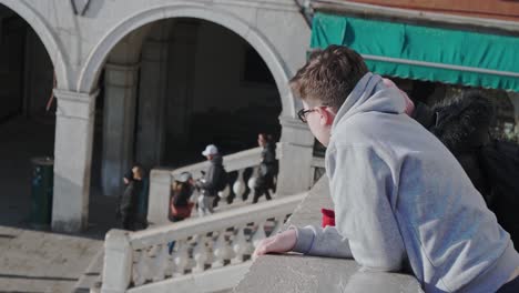 Young-boy-leaning-against-Rialto-Bridge-in-Venice-and-sightsee-surroundings