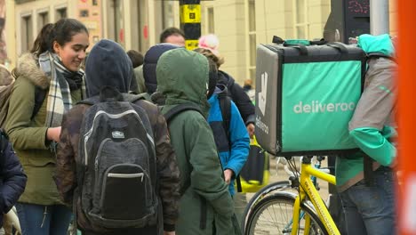 Deliveroo-Fahrer-Wartet-Unter-Schulkindern-Im-Geschäftigen-Stadtzentrum-Auf-Die-Nächste-Bestellung,-Gent,-Belgien