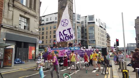 Demonstranten-Der-Extinction-Rebellion-Spielen-Und-Tanzen-Zu-Musik-Vor-Einem-Lila-Boot,-Das-Eine-Der-Hauptstraßen-Im-Stadtzentrum-Von-Glasgow-Blockiert