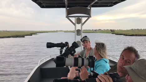 Photo-Safari-patrons-chat-during-a-quiet-lull-on-Chobe-River,-Africa