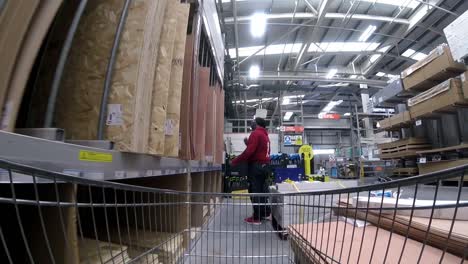 Inside-DIY-home-improvement-shopping-cart-pushing-trolley-down-wood-aisle-as-customers-shop-during-corona-virus-pandemic