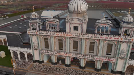 Imágenes-De-Drones-4k-Que-Revelan-La-Fachada-Frontal-Del-Templo-Hindú-Con-Una-Hermosa-Y-Elaborada-Escultura-Y-Una-Arquitectura-Simétrica-En-Medio-De-Una-Tierra-De-Cultivo,-Campos-De-Arándanos,-Montañas,-Nubes