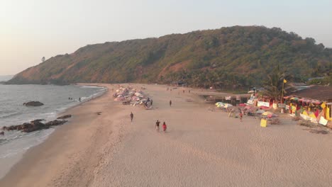 Menschen-Schlendern-Am-Strand-Von-Arambol-Entlang,-Dem-Ruhigen-Wasser-Des-Ozeans