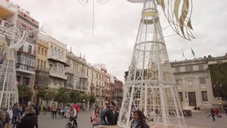 Giant-Christmas-angel-decorations-in-busy-square,-Seville,-Spain,-Tilt-Down