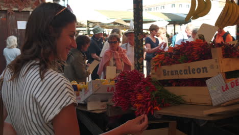 Close-up-shot-of-pretty-woman-checking-and-touching-fresh-bunch-of-red-spicy-pepper-on-italian-market