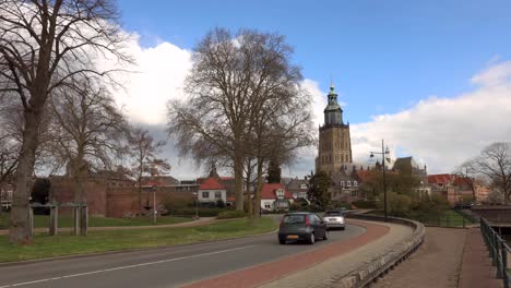 Zeitraffer-Von-Autos-Auf-Einer-Kurvenreichen-Stadtstraße-Mit-Der-Dahinter-Aufragenden-Walburgiskerk-Kathedrale-Vor-Einem-Blauen-Himmel,-über-Dem-Sich-Bedrohliche-Wolken-Entwickeln