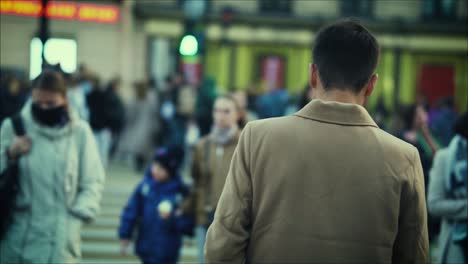 A-young-attractive-man-is-crossing-the-road-in-a-crowded-place-with-strangers-in-the-evening