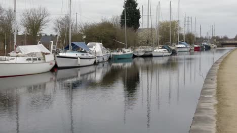 Kleine-Segelboote-Vertäut-Am-Ruhigen,-Ländlichen-Kanal-Yachthafen