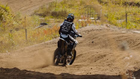 Conductora-De-Motocross-Y-Una-Competidora-Salen-Corriendo-De-Una-Esquina-En-Cámara-Lenta,-Volando-Tierra