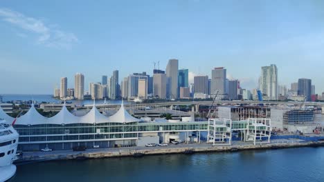 Vista-Aérea-De-Un-Puerto-De-Cruceros-En-Frente-Y-Fondo-Del-Paisaje-Urbano-Del-Centro-De-Miami-En-Video-Trasero-En-4k-|-Fondo-De-Video-De-Vista-Aérea-Del-Puerto-De-Cruceros-De-La-Ciudad-De-Miami