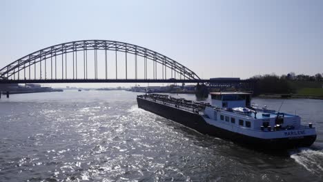 Petrolero-De-Marilene-Dejando-Retrolavado-En-El-Agua-Del-Río-Noord-Con-Puente-De-Arco-En-La-Parte-Delantera