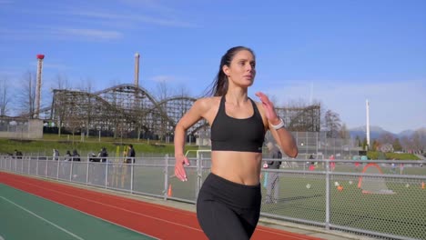 Young-athletic-woman-running-along-track-gimbal-shot