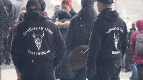 Plano-Medio-Amplio-De-Un-Par-De-Personas-En-Las-Protestas-De-Helsinki,-Vistiendo-Puentes-De-Soldados-De-Odín