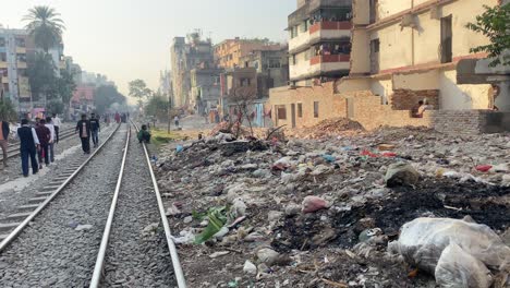 Basura-Esparcida-Al-Lado-De-Vías-De-Ferrocarril-Vacías-Con-Gente-Caminando-A-Lo-Largo-De-Ellas-En-Dhaka