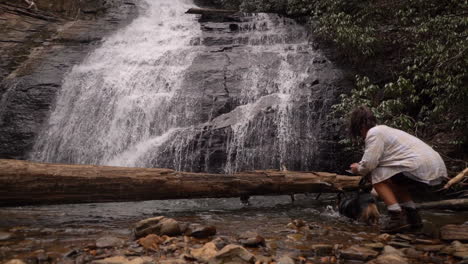 Un-Dueño-Y-Su-Perro-Caminan-Hacia-Una-Cascada-Y-Toman-Una-Foto---Perro-En-Cámara-Lenta-Jugando-En-El-Agua