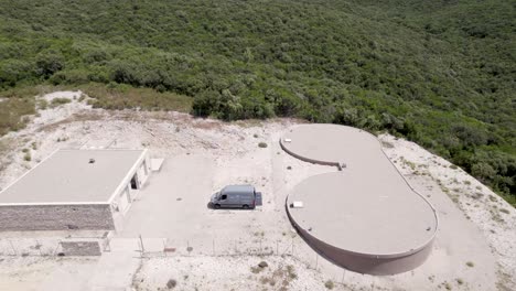 Mountain-water-reservoir-with-chemical-cleanup-van-parked,-Aerial-closing-in-shot