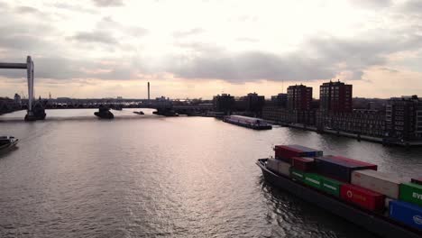 Aerial-Dolly-Over-Oude-Maas-With-Salute-Cargo-Vessel-Making-Approach-To-Spoorbrug-Railway-Bridge-During-Sunset-Skies