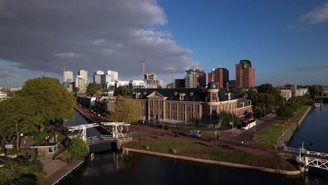 Antena-Ascendente-Que-Muestra-El-Museo-Muntgebouw-En-Utrecht-Con-Un-Pequeño-Puente-Levadizo-Sobre-El-Canal-En-Frente-En-Un-Día-Soleado-Con-El-Distrito-Financiero-Revelado-En-El-Fondo