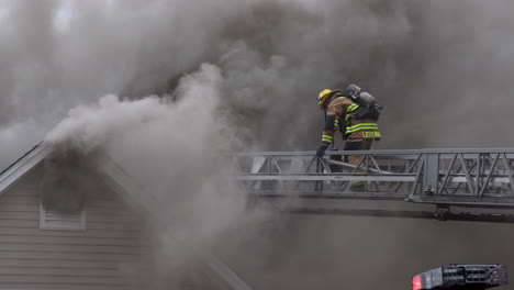 Dos-Bomberos-Caminan-Por-Una-Escalera-Extendida-Hacia-El-Humo-Espeso-Y-Oscuro-De-Una-Casa-En-Llamas