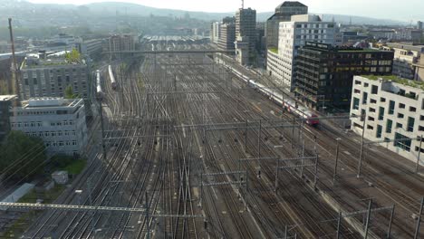 Toma-Aérea-Fija-Del-Tren-Que-Sale-De-La-Estación-Central-De-Zúrich