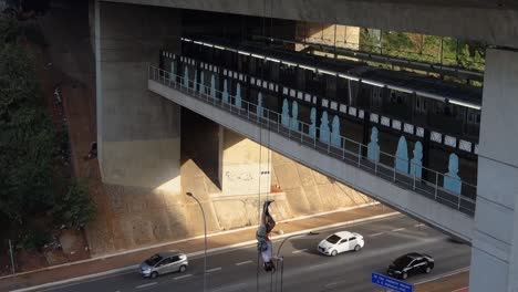 Hombre-Boca-Abajo-Rapelando-Desde-Un-Viaducto-Sobre-La-Concurrida-Avenida