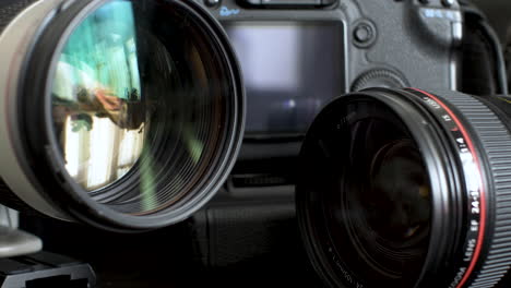 Pair-Of-Canon-Telephoto-Lens-On-Desk-With-Body-Of-DSLR-Camera-Body-In-Background