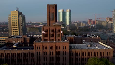 Front-exterior-facade-of-Inktpot-building-with-UFO-resting-on-it-at-sunrise-with-central-train-station-and-shiny-architecture-of-Utrecht-in-the-background