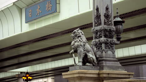 Tokio,-Japan,-Ca.-April-2020:-Fußgänger-Gehen-Auf-Der-Historischen-Nihonbashi-Brücke-Mit-Sitzendem-Geschnitzten-Löwen,-über-Der-Autobahn,-In-Der-Altstadt-Im-Zentralen-Finanzviertel,-Frühlingsabend