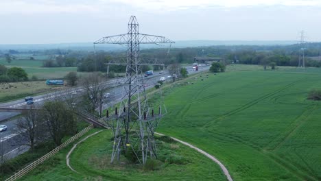 Fahrzeuge-Auf-Der-Autobahn-M62,-Vorbei-Am-Pylonturm-Auf-Landwirtschaftlichen-Feldern,-Luftaufnahme-Aufsteigend