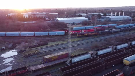 Luftaufnahme-über-Lange-Gleise-Und-Güterschiff-Tankwagen-Eisenbahnlinien,-Die-Sich-Bei-Sonnenaufgang-Nach-Rechts-Neigen