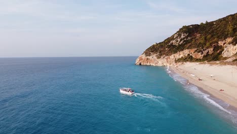 Taxi-Barco-Transporta-Turistas-Desde-La-Playa-De-Milos-Hasta-Agios-Nikitas-En-La-Isla-De-Lefkada,-Grecia---Antena