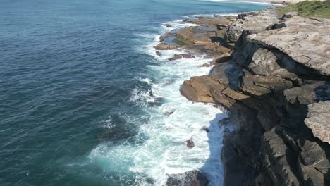 Vista-Aérea-De-Las-Olas-Del-Océano-Rompiendo-Las-Rocas-En-La-Costa-De-Sydney