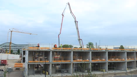 Grúas-Moviéndose-Y-Dispersando-Material-De-Construcción-Donde-Sea-Necesario-En-El-Sitio-De-Construcción-Puur12-Contra-Un-Cielo-Azul-Con-Nubes-Que-Se-Forman-Y-Pasan