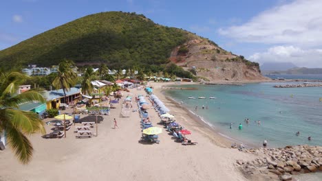 Vista-Aérea-Frente-A-La-Gente-En-La-Playa-De-Frigate-Bay-En-Saint-Kitts-Y-Nevis--Seguimiento,-Disparo-De-Drones