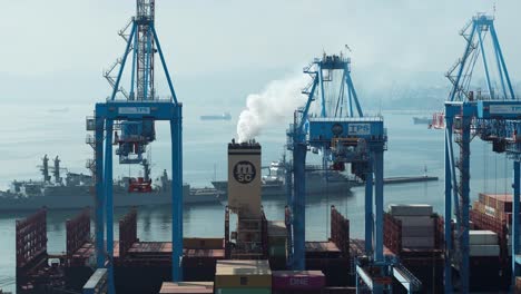 Container-cargo-ship-docked-near-cranes,-vapor-in-air,-ready-to-be-loaded-in-Valparaiso-Sea-Port,-Chile