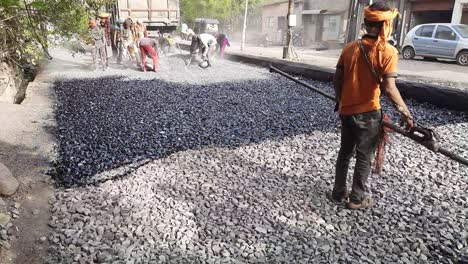 Eine-Nahaufnahme-Von-Arbeitern,-Die-Den-Bau-Von-Asphaltstraßen-Oder-Damar-Straßen-Arrangieren-–-Arbeiter,-Die-Asphalt-Auf-Die-Stadtstraße-In-Indien-Sprühen