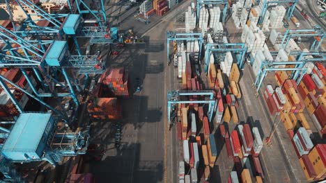 Aerial-dolly-in-of-stacked-containers-near-cranes-waiting-to-be-loaded-on-a-cargo-ship,-Valparaiso-Sea-Port,-Chile