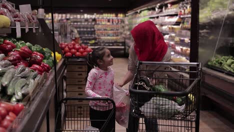 Niña-Ayudando-A-La-Madre-En-La-Tienda-De-Comestibles,-Poniendo-Verduras-En-Una-Bolsa