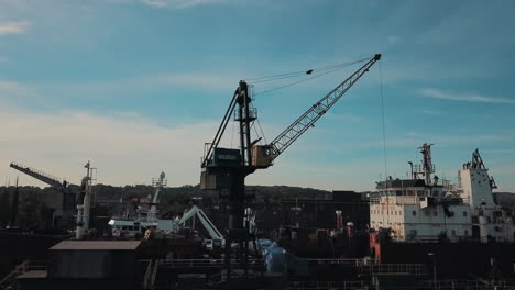 Drohne-Fliegt-Um-Kran-Herum,-Während-Frachtschiff-In-Docks-Geladen-Wird