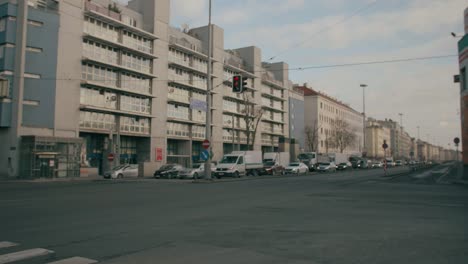 Crossroads-with-many-vehicles-and-cars-crossing,-in-the-middle-of-Vienna,-Austria,-near-houses-and-buildings,-on-a-sunny-day-with-some-clouds