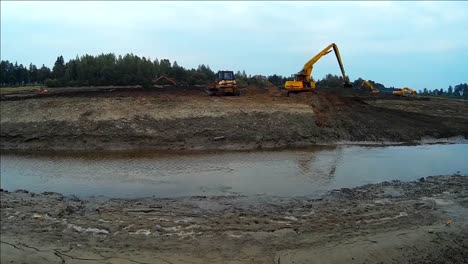 La-Excavadora-Amarilla-Trabaja-Con-Un-Balde-Para-Limpiar-Lodos-De-Lodo-Y-Escombros-Del-Fondo-Del-Río-Drenado