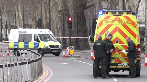 A-team-of-three-paramedics-stand-behind-an-ambulance-inside-a-police-cordon