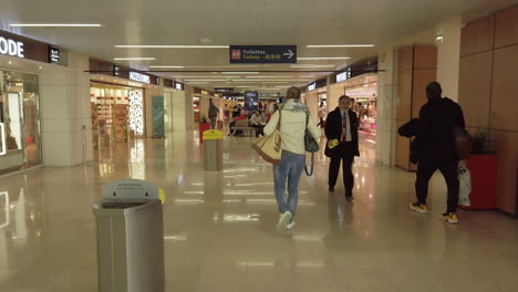 Siguiendo-A-Los-Pasajeros-En-El-Interior-Del-Aeropuerto-De-Orly-En-Su-Camino-Hacia-El-Embarque-Y-El-Paso-Frente-A-Las-Tiendas-Libres-De-Impuestos